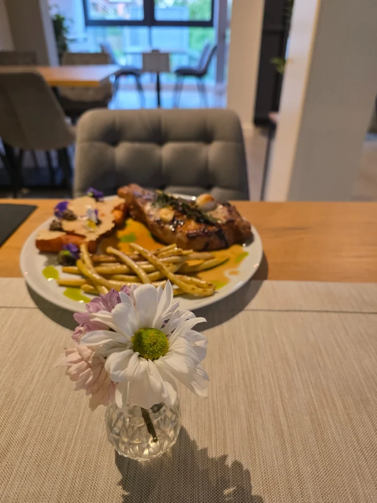Danie główne w restauracji Le Vert z kwiatami na stole